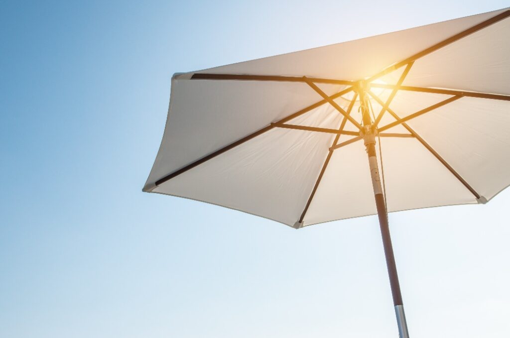 Luxuriöser Regenschirm in der Sonne gegen den blauen Himmel. Heiße Sommer Entspannung und Urlaub Konzept.