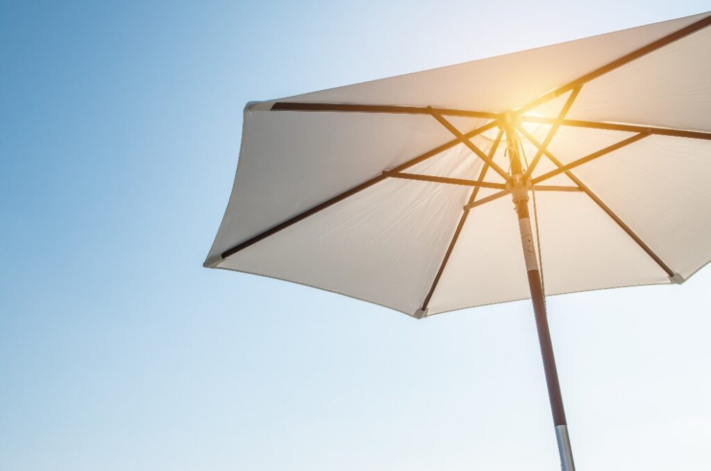 Luxuriöser Regenschirm in der Sonne gegen den blauen Himmel. Heiße Sommer Entspannung und Urlaub Konzept.