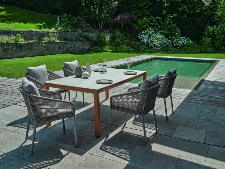 Moderne Terrasse mit Tisch und Stuehlen am Pool in Gruen und Grau